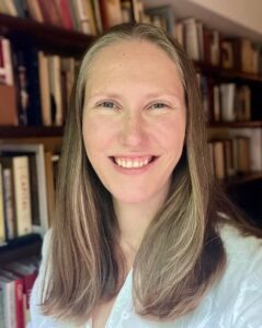 Emilyi Le Roux-Rutledge smiles for the camera in front of a full book case