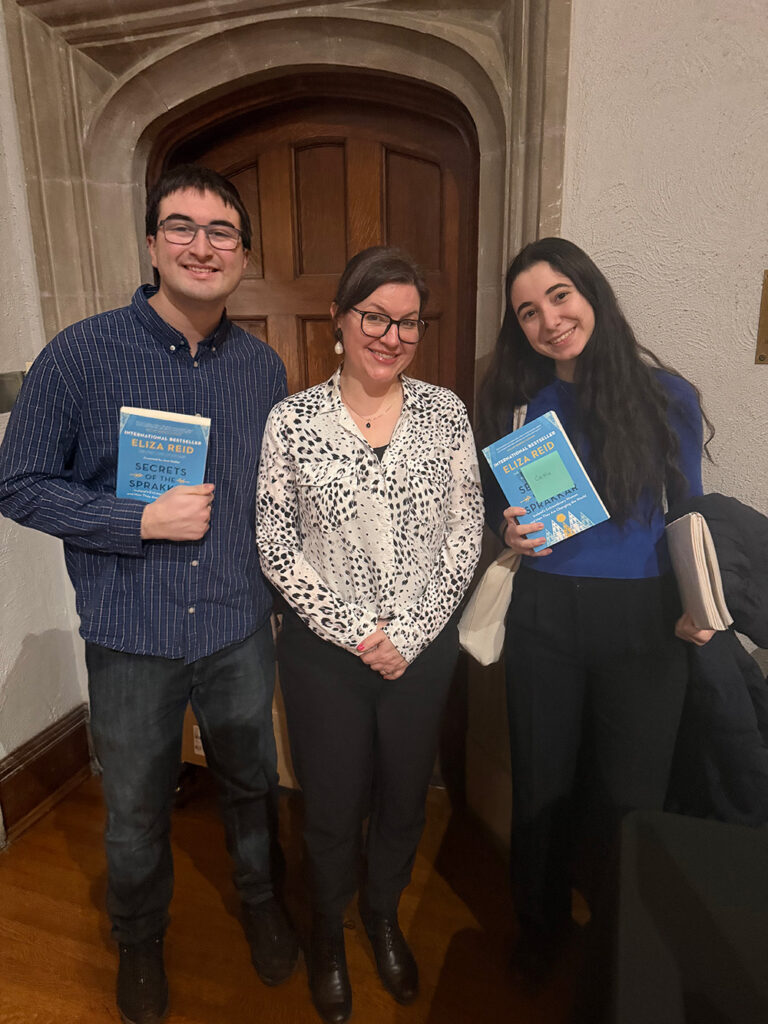 Eliza Reid stands with two people holding her book