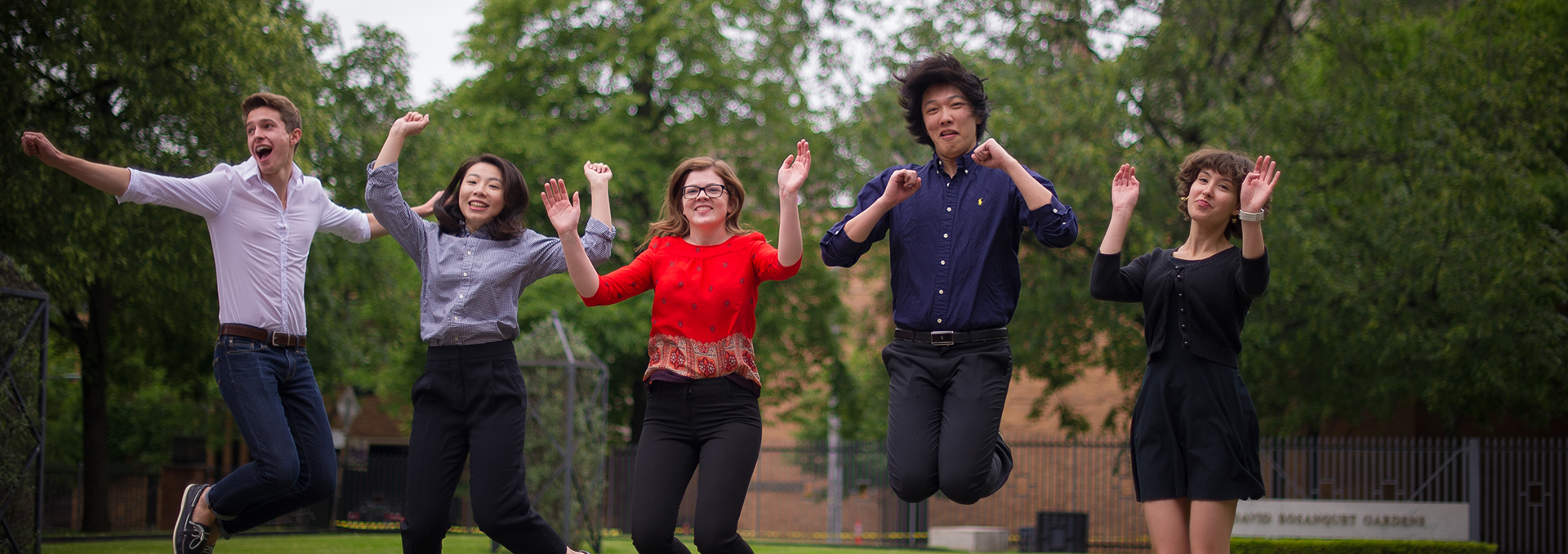 Five students jumping in the Bosanquet Gardens at the John W Graham Library