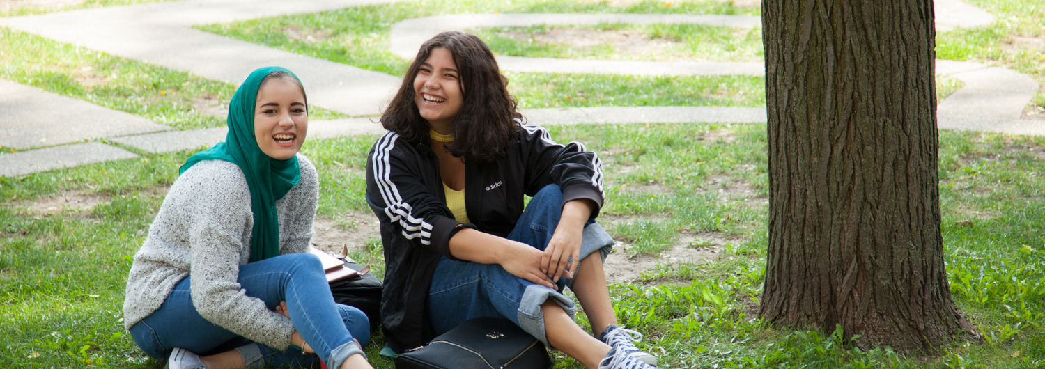 Two students sitting on the grass in the Trinity Quad