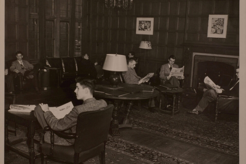 Sepia toned photo of a common room with young men in suits